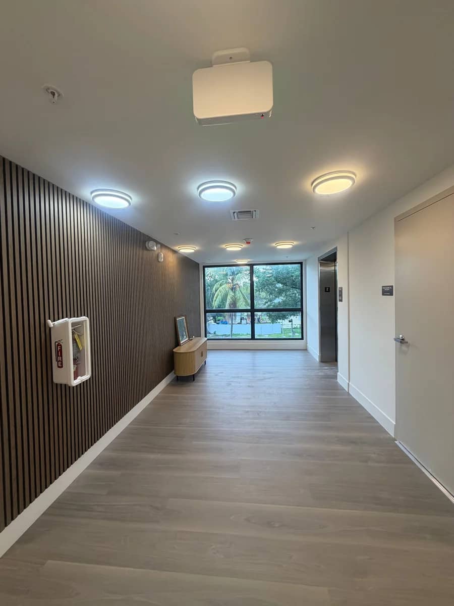 Aventura Quattro, photographed 14 April 2026: the ground-floor corridor finished — lighting, flooring and the slatted wall.