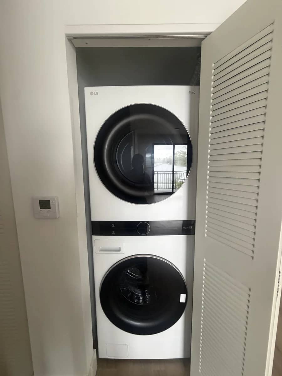 Aventura Quattro, photographed 22 May 2026: in-unit stacked washer and dryer behind louvred doors.