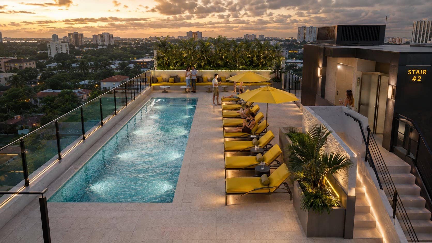 The roof deck and pool at dusk, with loungers and the skyline beyond.
